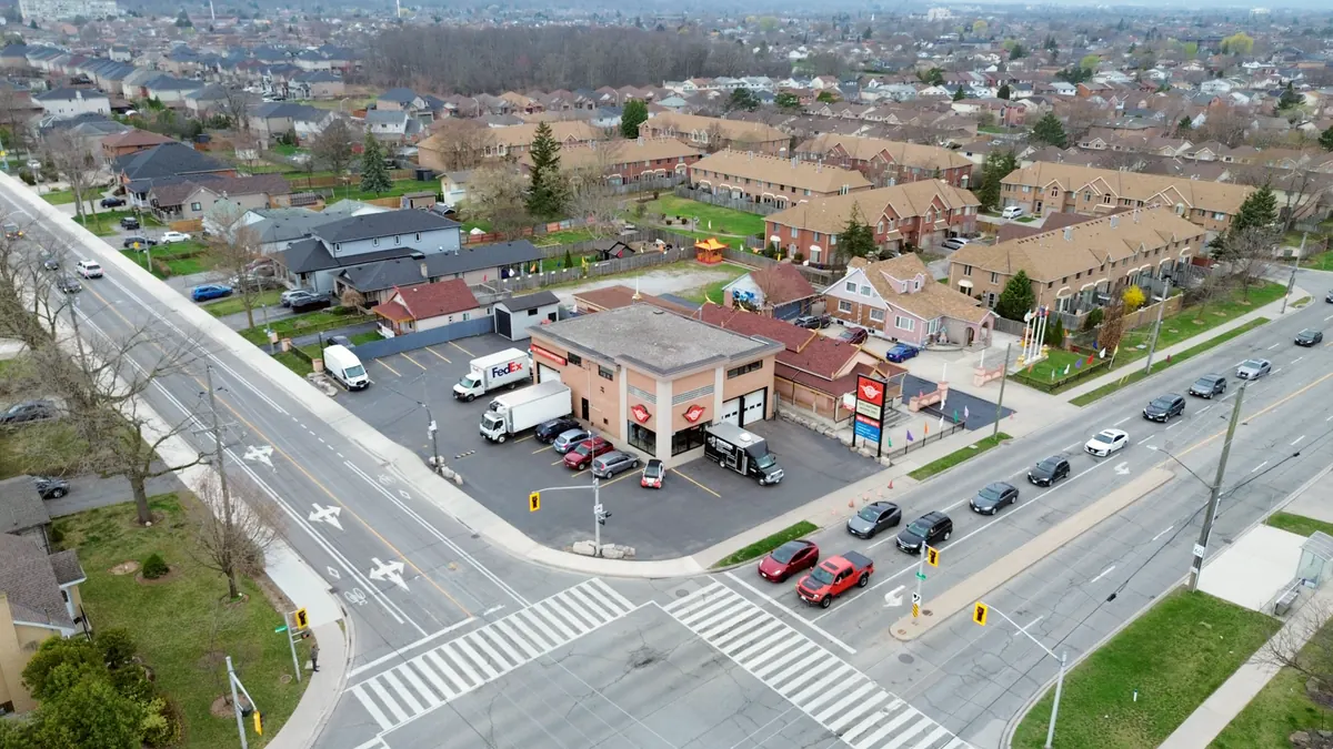 Aerial view of the corner of Barton Street East and Dewitt Road: the two-storey building, its lot, and cars queued at the signal