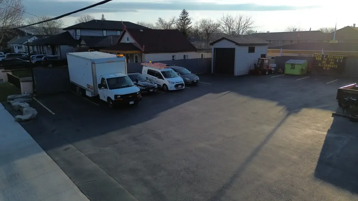 The rear lot at dusk: parked trucks and cars, and the small rear structure with its dark roll-up door