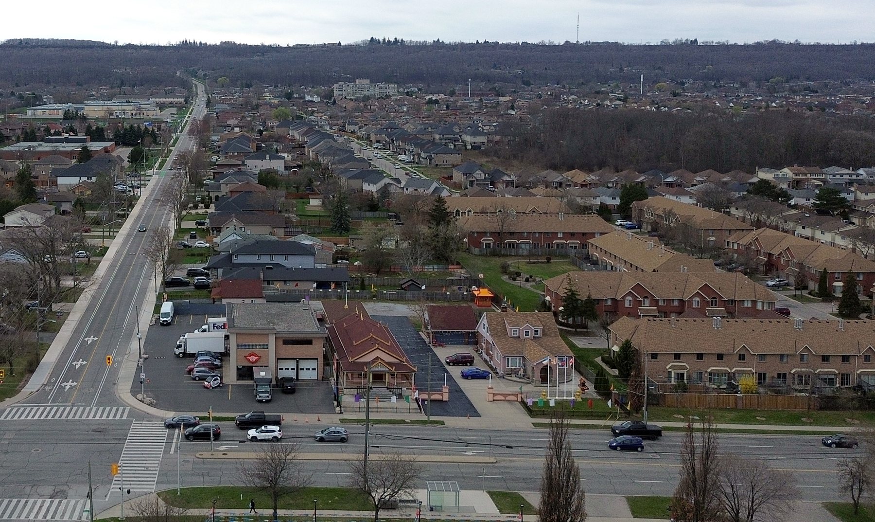 Aerial looking south along Dewitt Road: the corner building and its lot, rows of townhouses to the west, detached houses along the side streets, and the wooded escarpment on the horizon