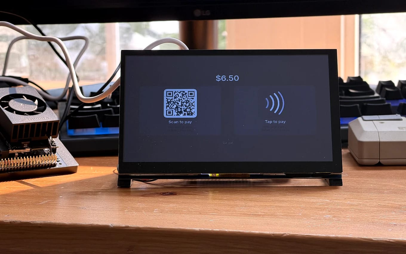 The bench unit’s checkout screen seen from the side, the scan-to-pay and tap-to-pay tiles at an angle.
