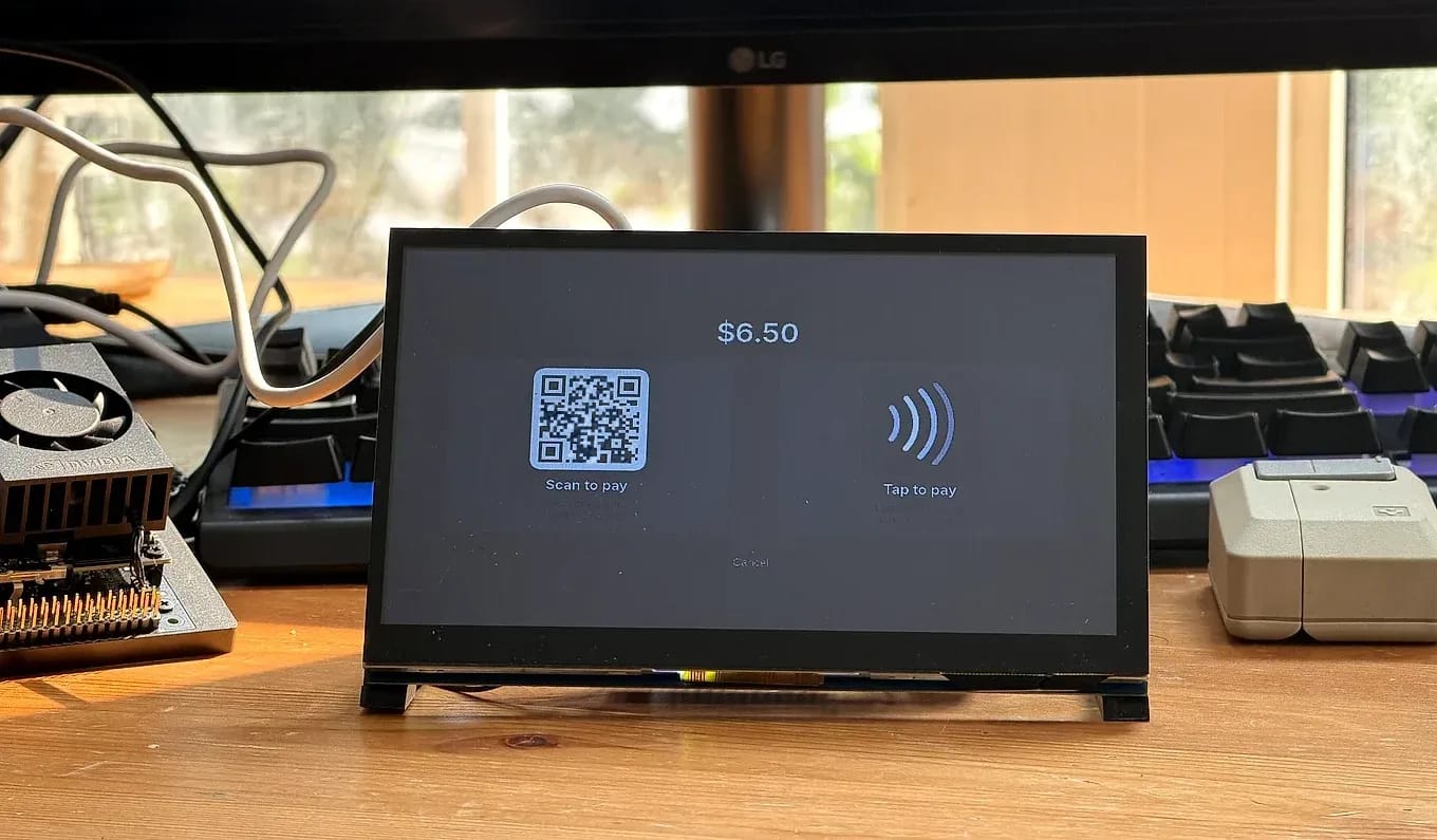 The bench unit on a workbench, its touchscreen showing checkout: total $6.50 with a scan-to-pay QR beside a contactless tap-to-pay symbol.