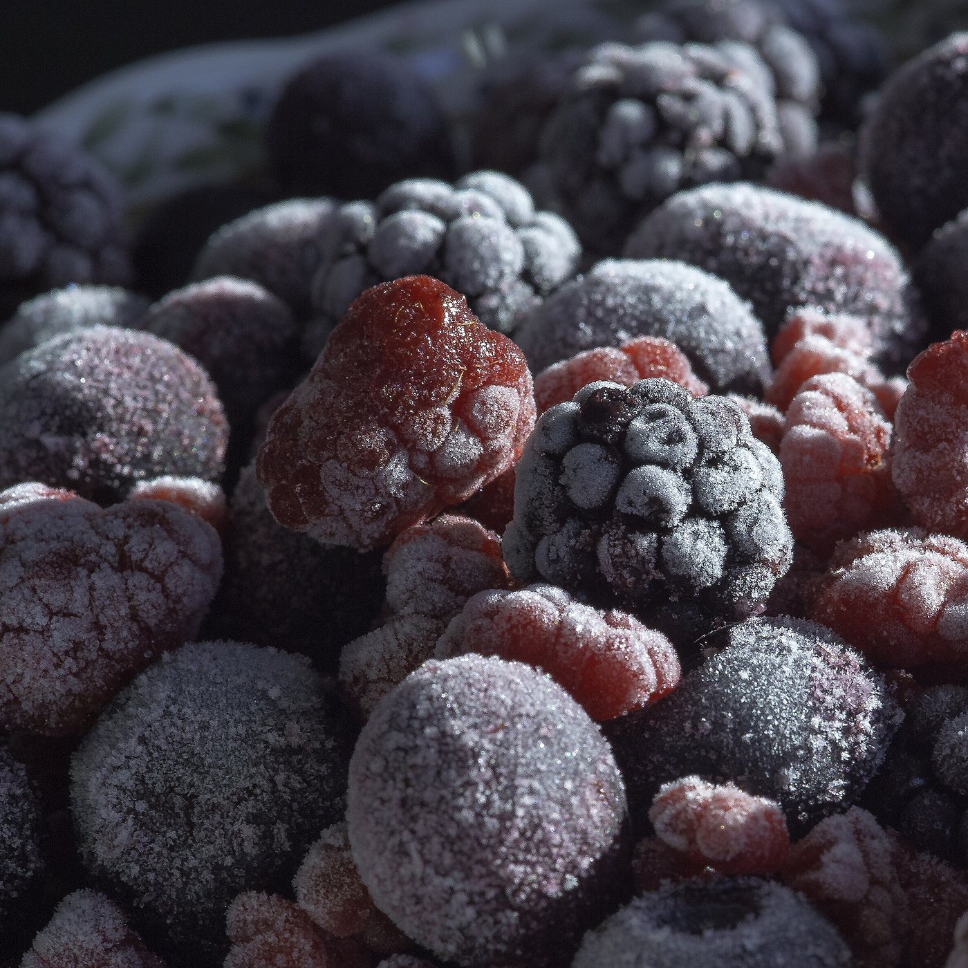 Frost-covered frozen raspberries, blackberries and blueberries