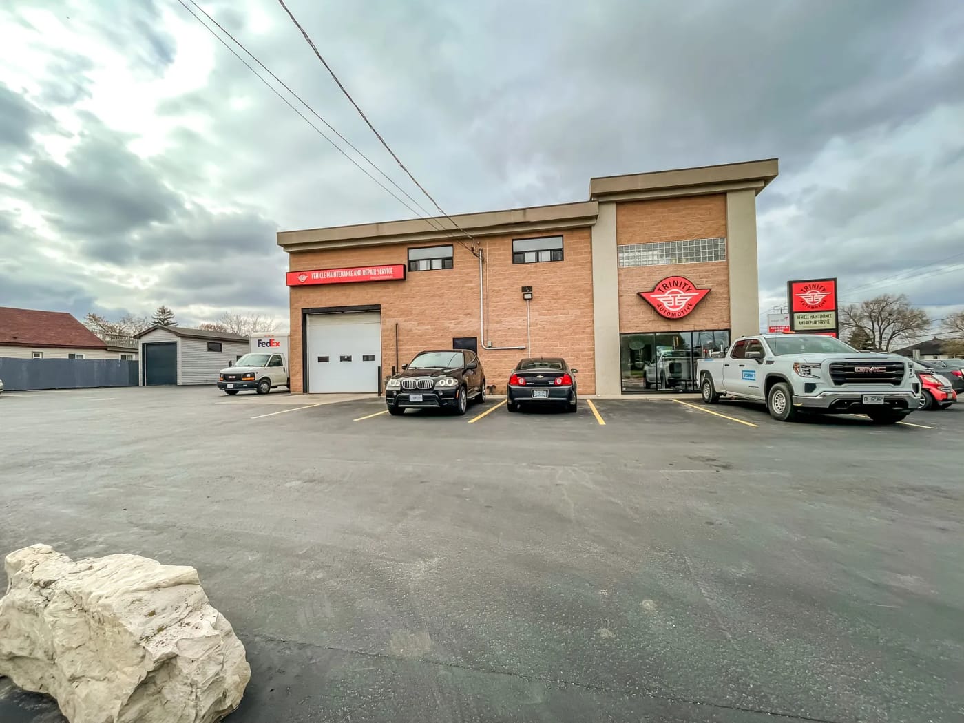 The building’s long east face, a single bay door at its south end, with vehicles parked against it