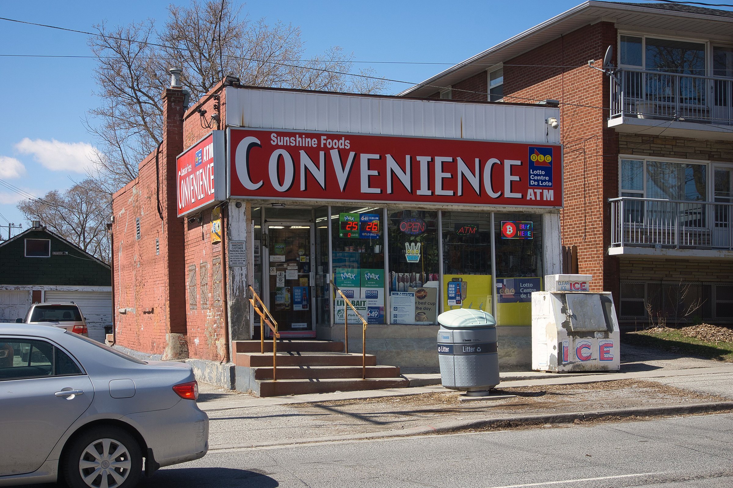 An independent convenience store on a Toronto street, its red Convenience sign over the door