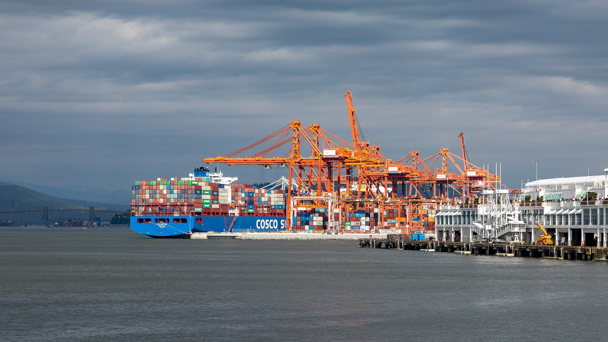 Orange container cranes and a loaded container ship at the Centerm terminal in Vancouver harbour