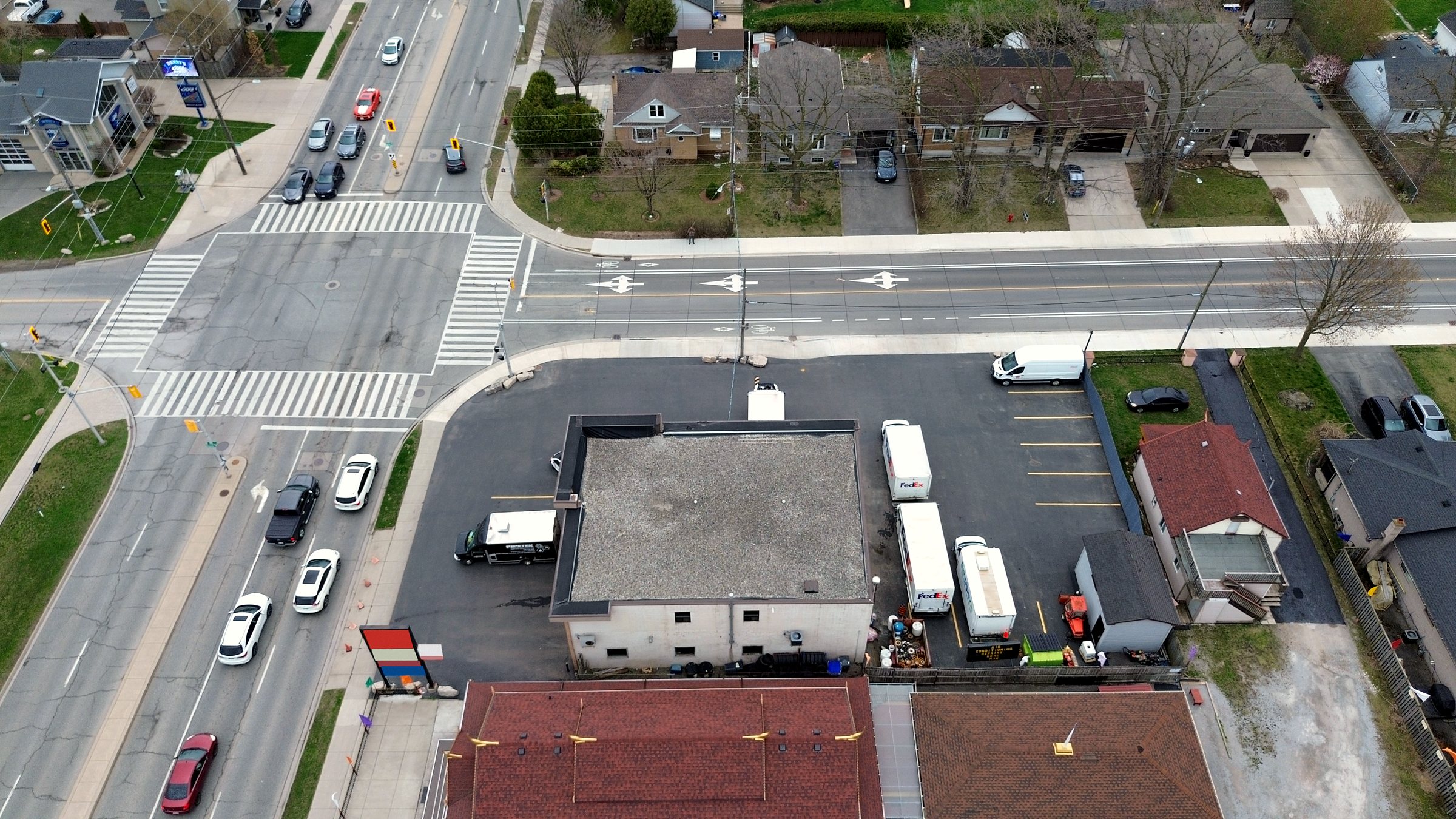 The building and its paved lot seen almost straight down from above, delivery trucks parked along one side