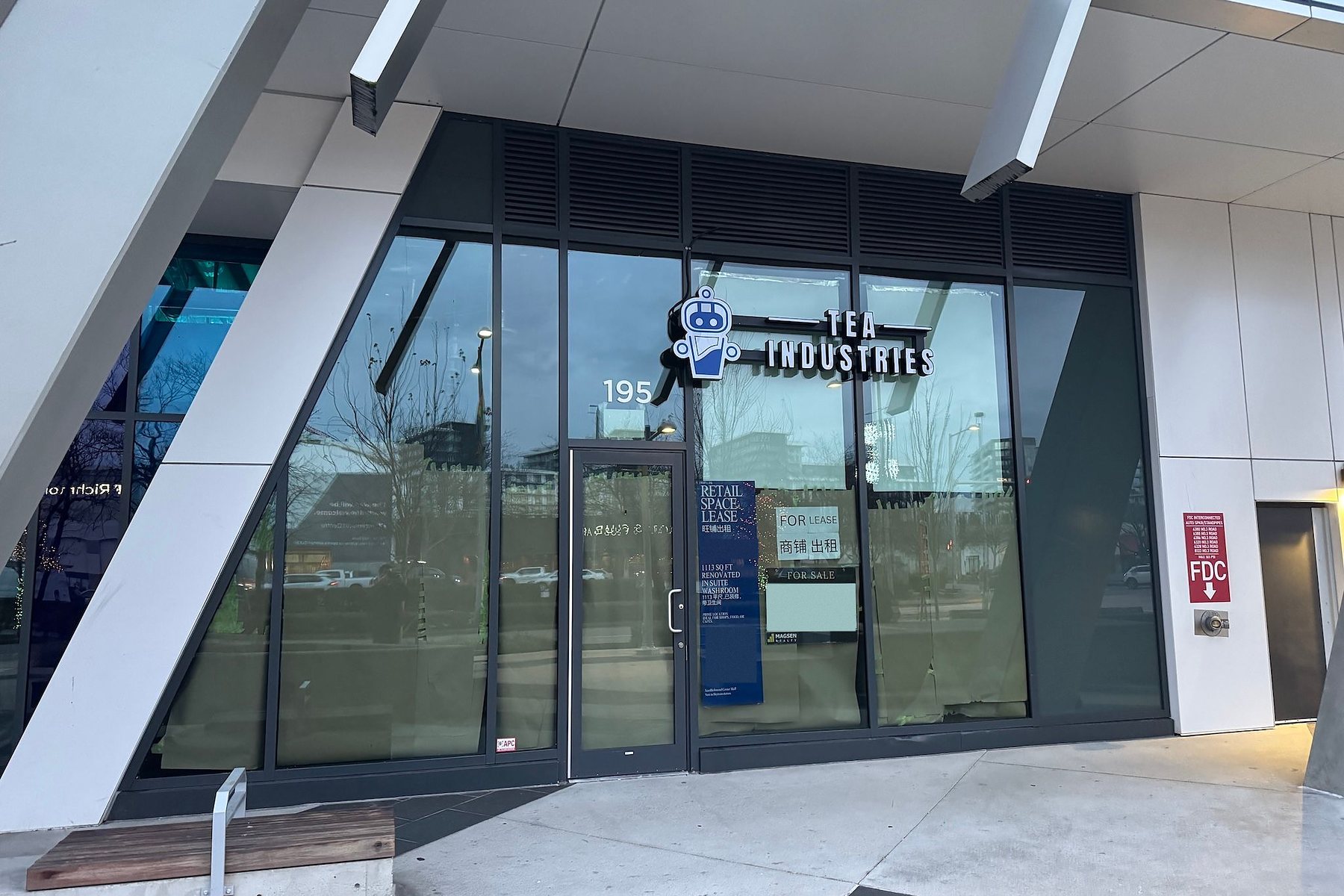The closed Tea Industries storefront: the sign still mounted over papered-over windows with lease and sale notices